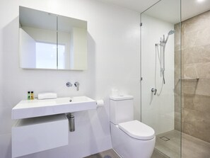 Une salle de bain moderne avec un lavabo blanc, des toilettes et une douche à parois de verre.