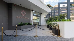 Entrada de un edificio moderno con un logotipo geométrico, una puerta de cristal y una barrera de cuerda negra.
