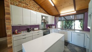 A modern kitchen with white cabinets, a central island, a gas stove, and a window providing a view of greenery outside.