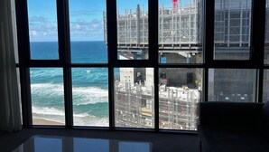 Una habitación con ventanas amplias que dan a una obra en construcción y al océano.