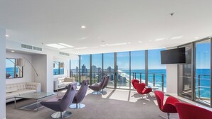 Un salón moderno con ventanas amplias, un sofá y sillones rojos y morados.