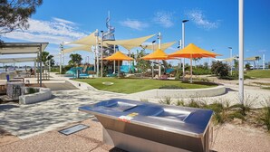 A park with a pool, seating areas, and umbrellas.