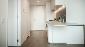 A modern kitchen with a central island, white cabinetry, and a wooden floor.