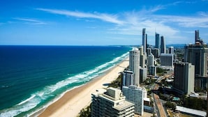 Eine Küstenlandschaft mit Hochhäusern, einem Strand und dem Meer.