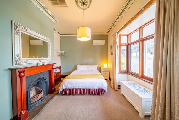 A bedroom with a fireplace, a bed, a window, and a bedside table. - Condor Estate Spacious with Vineyard and Fireplace (Maslin Beach)