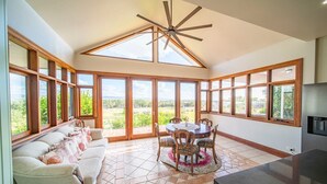 A spacious kitchen with large windows, a dining area with a table and chairs, and a ceiling fan. - Condor Estate Spacious with Vineyard and Fireplace (Maslin Beach)