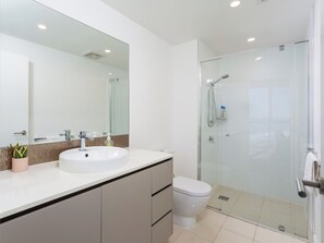 A modern bathroom with a white sink, a glass shower enclosure, and a toilet. - Level 22 1BR | Ocean View Apartment | 50m to Beach (Surfers Paradise)