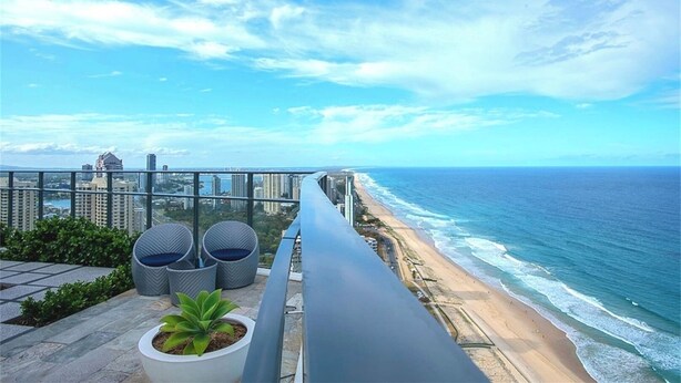A balcony with a view of the ocean and city skyline.