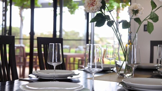 A dining table set with plates, glasses, and a vase with flowers. - The Red Door @ Barossa Valley ★Vineyard View★ (Nuriootpa)