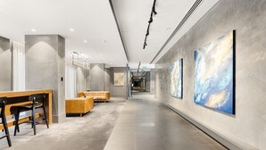 Eine moderne Hotelhalle mit langer Diele, Sitzgelegenheiten und großen abstrakten Gemälden an den Wänden.