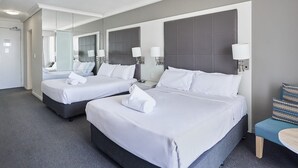 Une chambre d’hôtel avec deux lits, un grand miroir et un petit coin salon.