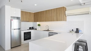 A modern kitchen with white cabinetry, a stainless steel refrigerator, a built-in oven, and a dishwasher.
