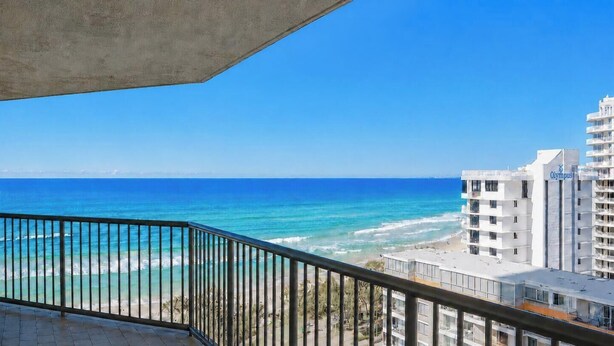 A balcony with a view of the ocean and a building with the name 'Olympus' on it.