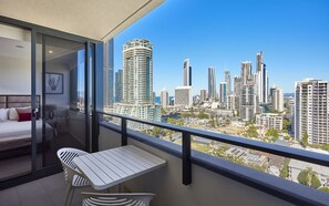 Een balkon met uitzicht op de stad, een bed, en een kleine tafel met stoel.