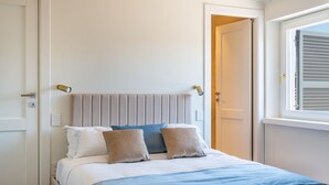 A bedroom with a bed, a window with blinds, and a door. - iFlat | Luxury Penthouse Piazza Venezia (Roma)