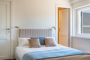 Une chambre à coucher avec un lit, une fenêtre avec des stores et une porte.