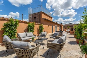 Eine Terrasse im Freien mit Korbmöbeln, einem kleinen Tisch und Topfpflanzen.