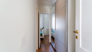 A narrow hallway with a wooden floor, white walls, and a door with a gold handle. - iFlat | Luxury Penthouse Piazza Venezia (Roma)