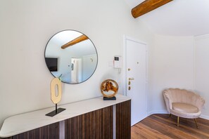 A room with a round mirror, a wooden number display, a decorative object, a white door, and a pink chair.