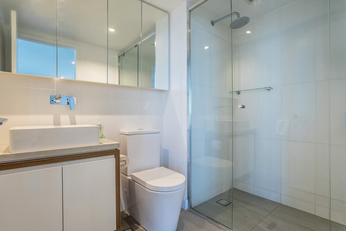 A modern bathroom with a glass shower enclosure, a white sink, and a toilet.