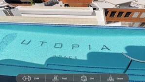 A swimming pool with 'UTOPIA SPACE' written on the water, surrounded by buildings.
