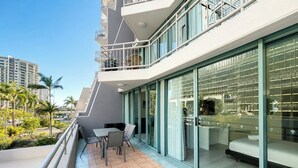 A modern hotel balcony with a dining area, large sliding glass doors, and a view of the cityscape. - Crown Towers Stunning 1Bedroom Apt 3-min to Beach (Surfers Paradise)
