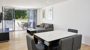 A modern living room with a white table, grey sofas, and a balcony with outdoor furniture. - Exquisite and Stylish Villa in Surfers Paradise (Surfers Paradise)