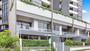 A modern apartment building with balconies, a gated entrance, and a well-maintained garden. - Exquisite and Stylish Villa in Surfers Paradise (Surfers Paradise)