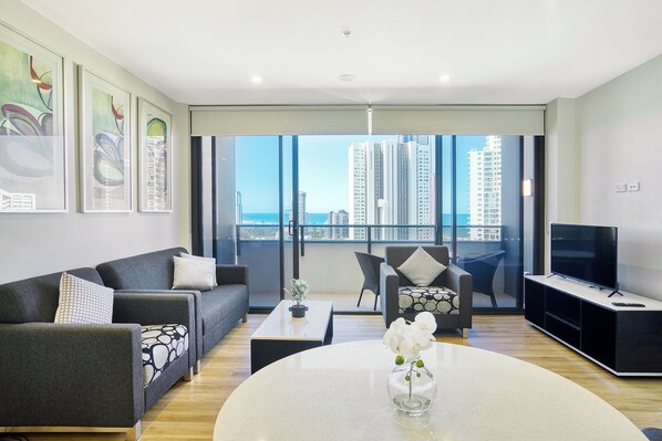 A modern living room with a sofa, armchair, coffee table, and TV stand.