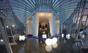 A spacious atrium with a high ceiling and a central staircase leading to upper levels.
