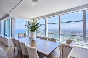 A spacious conference room with a large table and chairs, a white vase with flowers, and a panoramic city view through large windows.