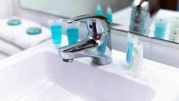 Une salle de bain moderne avec un robinet chromé, un lavabo blanc et un miroir qui reflète les articles de toilette.