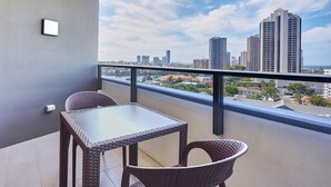 Un balcón con mobiliario de mimbre, vistas a un horizonte urbano y el edificio de un hotel Marriott.