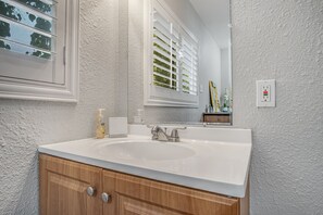 Sink and vanity area with mirror and window.