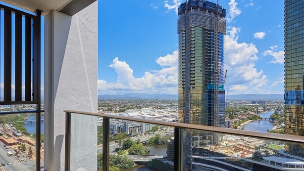 Un balcón con vistas a un río, un puente y una zona de construcción con un edificio alto en construcción.