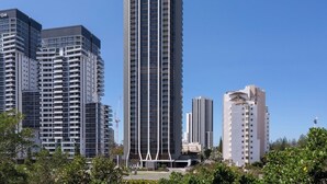 Un moderno edificio de gran altura con un llamativo letrero de 'AVANI' en la parte superior, rodeado de otros edificios altos.
