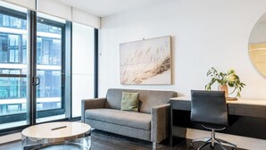 Un espacio de oficina moderno con sofá, escritorio, silla y un ventanal grande.