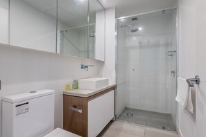 Un bagno moderno con doccia a pareti in vetro, un lavandino bianco e uno specchio sopra il mobile.
