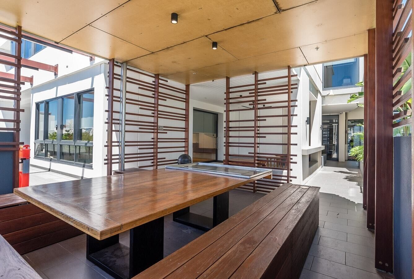 An outdoor dining area with a wooden table and benches, surrounded by a wooden fence with horizontal slats.