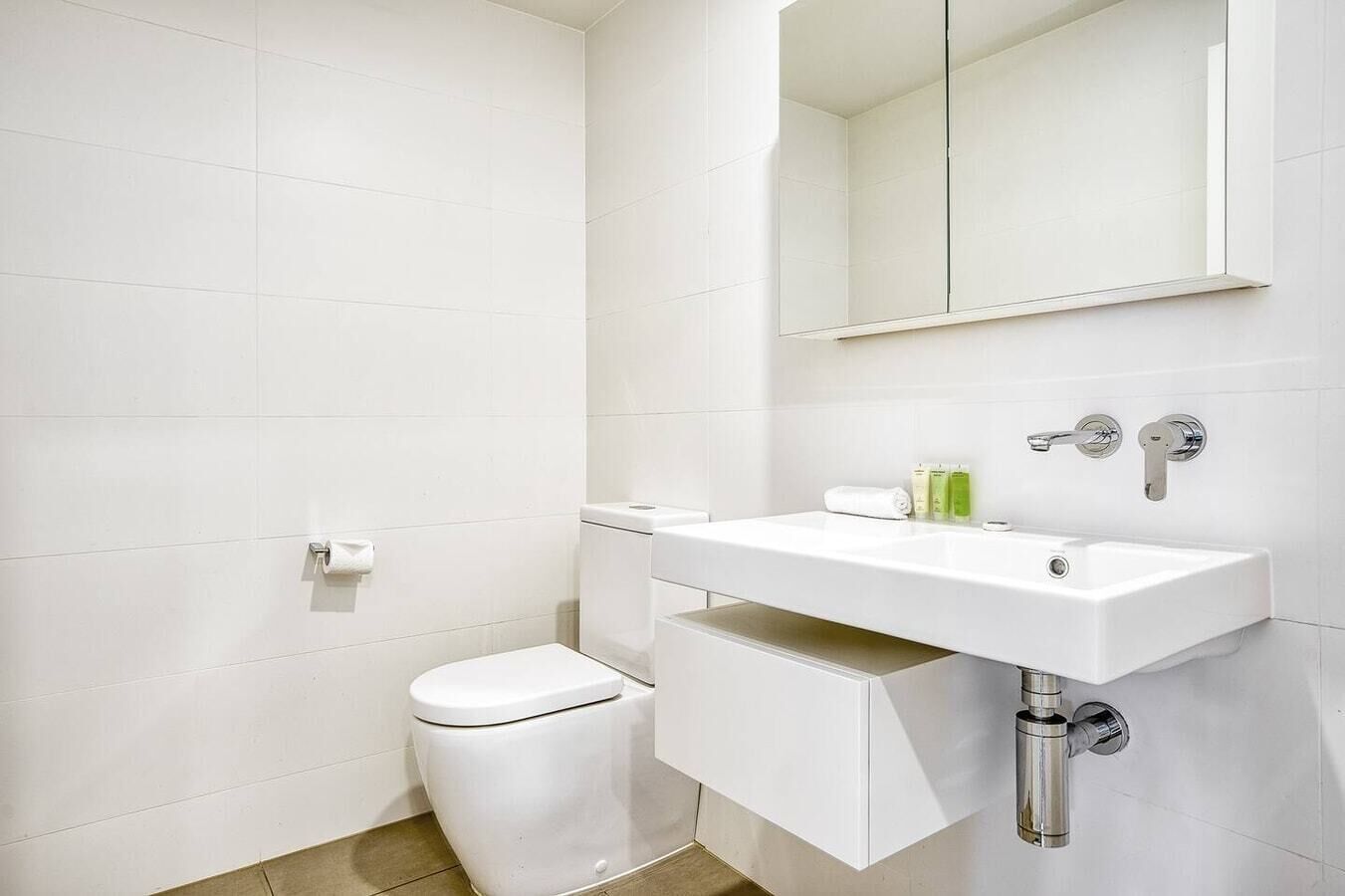 Ein modernes Badezimmer mit Toilette, Waschbecken mit Spiegel und Handtuchhalter.