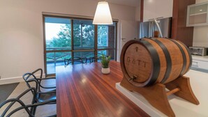 A modern kitchen with a wooden table, chairs, a potted plant, and a wooden barrel. - The Hideaway by Gatt Wines (Flaxman Valley)