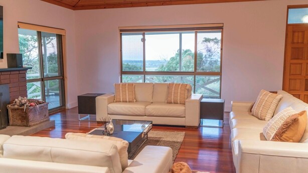 A spacious living room with a large window, a fireplace, and two sofas. - The Hideaway by Gatt Wines (Flaxman Valley)