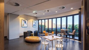 Un interior moderno con un ventanal grande, un banco de madera redondo y varias sillas alrededor de una mesa.