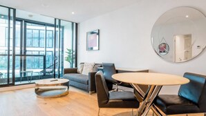 Una sala de estar moderna con un sofá, sillones, una mesa redonda y un espejo grande.