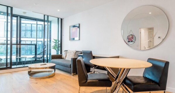 Una sala de estar moderna con un sofá, sillones, una mesa redonda y un espejo grande.