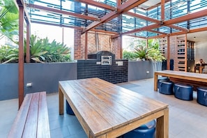 Enjoy casual dining in a serene outdoor setting surrounded by lush greenery and a brick oven.