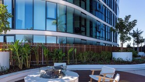 Un bâtiment moderne doté de grandes fenêtres en verre, d’une clôture en bois et d’un espace extérieur circulaire aménagé avec des chaises et une table.