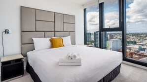 Une chambre d’hôtel moderne avec un grand lit, une vue sur la ville et une table de chevet avec une lampe.
