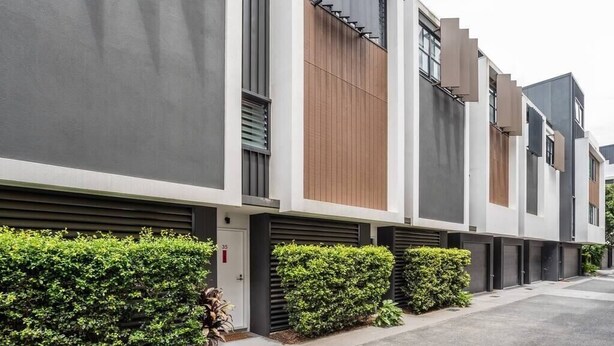 Ein modernes Wohngebäude mit minimalistischem Design, das sich durch klare Linienführung und eine Kombination aus Beton und Holzverkleidung auszeichnet.