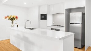 A modern kitchen with a central island, stainless steel appliances, and white cabinetry.